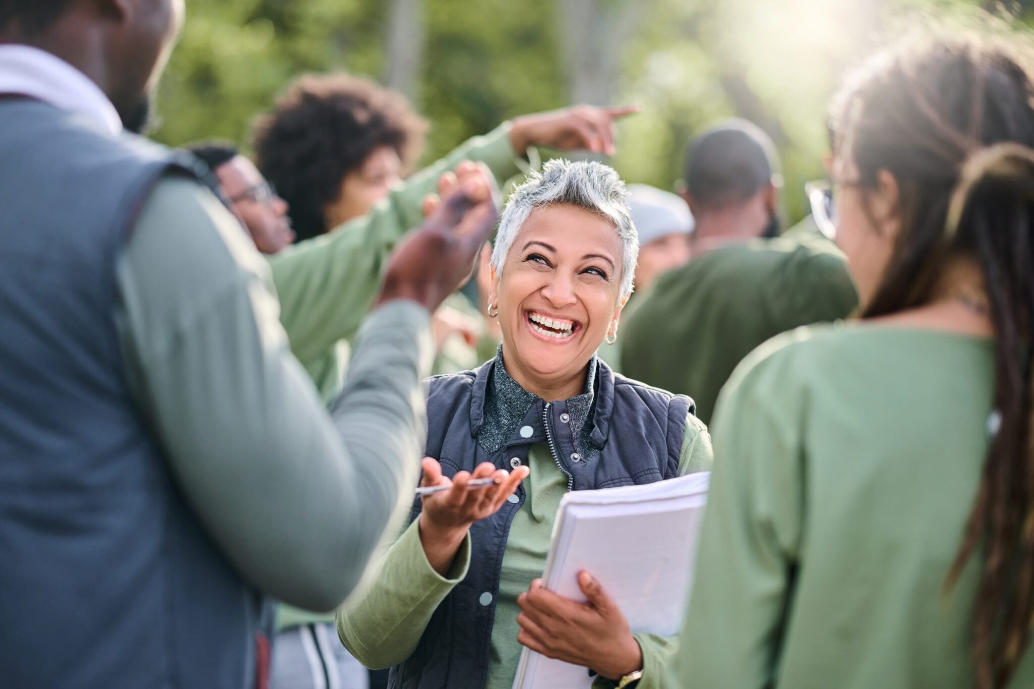 A woman smiling and talking to people while holding surveys.